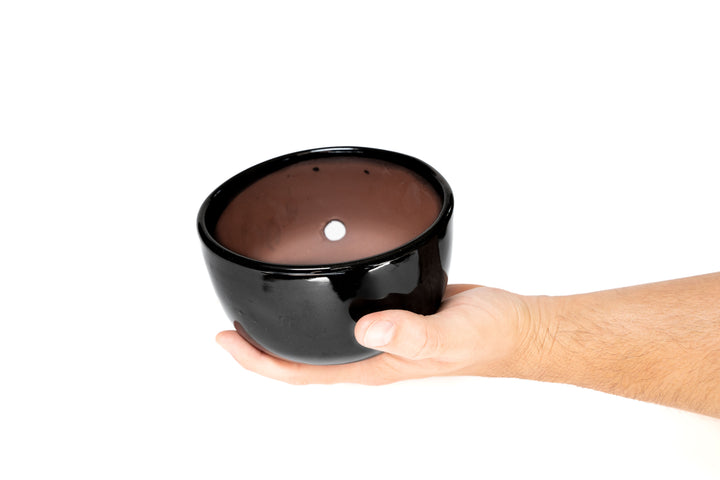 black glazed terracotta dish with hole for drainage